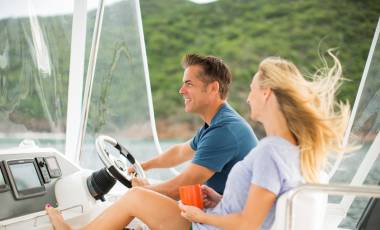 Couple enjoying the wind in their hair while cruising on a power catamaran